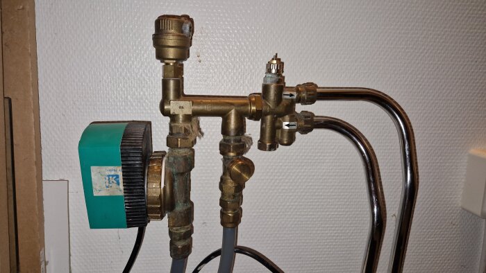 Värmefördelare med rör och en cirkulationspump installerad på en vägg, en del av ett golvvärmesystem.