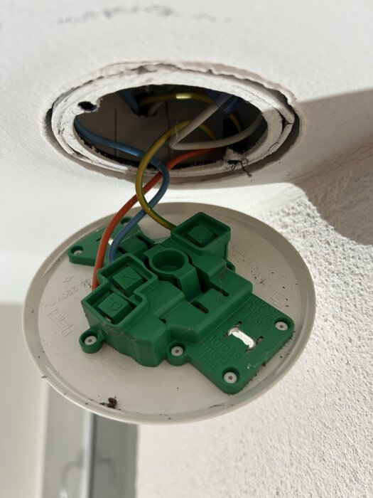 Takanslutning med grön kopplingsplint, lösa kablar synliga. Problem med metallflärpar som hindrar ny koppling från att passa i dosan.