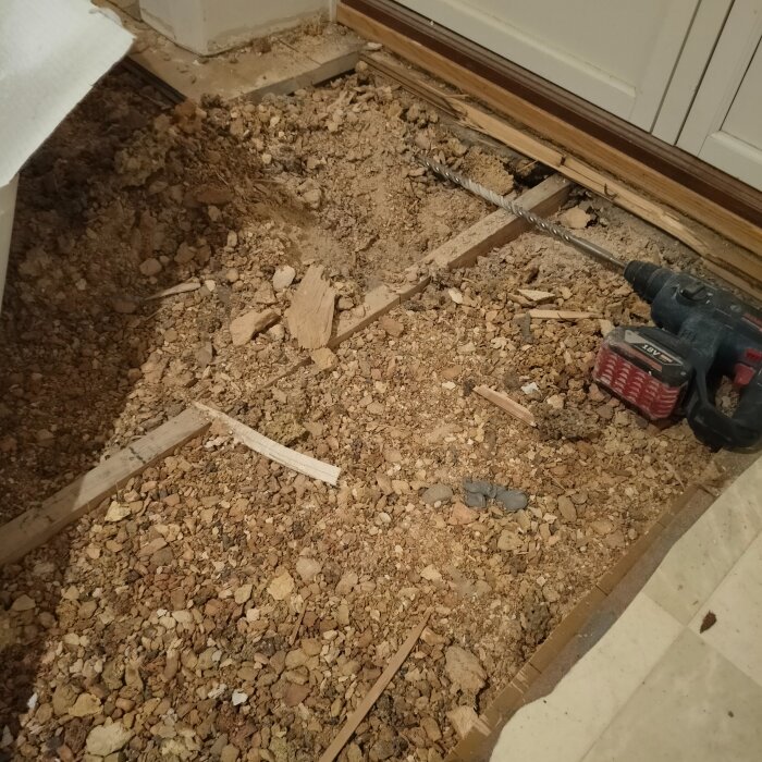 Renoveringsarbete i köket med synliga reglar och slaggsten. En borrmaskin ligger på golvet.