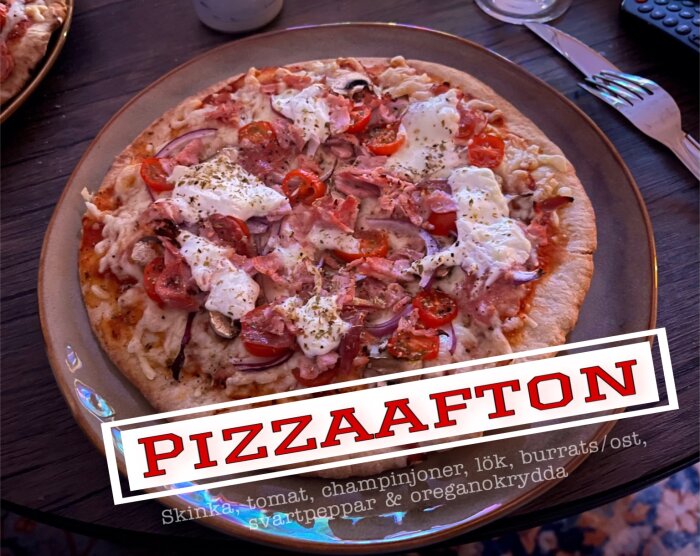 Hemlagad pizza med skinka, tomat, champinjoner, lök, burrata, svartpeppar och oreganokrydda på tallrik.