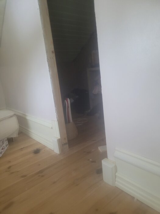 En nybyggd klädkammare med trädetaljer och väggar som nyligen målats. På golvet syns parkett med några små mörka fläckar.