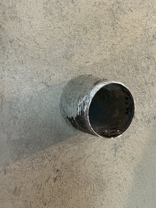 Rund svartmetallrör installerat i en betongvägg, godkänt av sotaren enligt forumdiskussion.