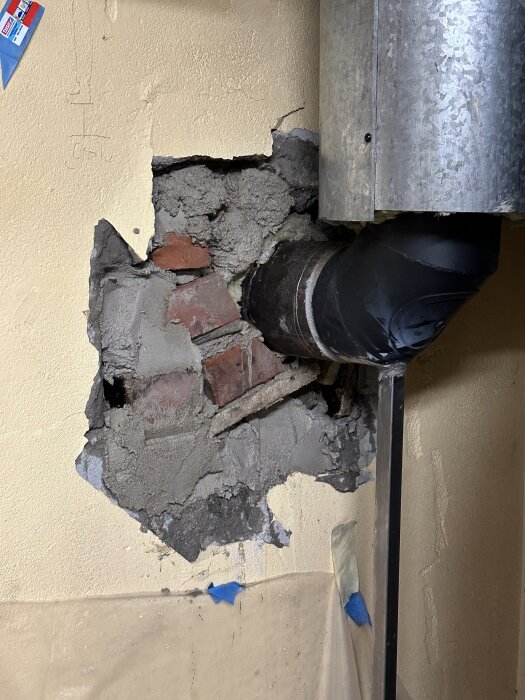 Brustet vägg med tegel och cement, rör tränger igenom, godkänt arbete efter granskning, trots tidigare tvivel från eldbutik.