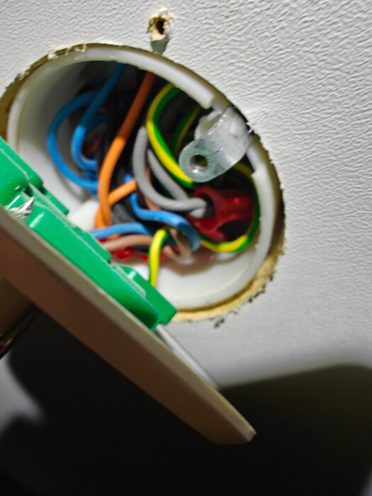 Elektrisk kopplingsdosa med synliga ledningar i olika färger, ansluten till en termostat.