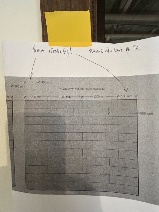 Schema av tegelfasads mönster, med handskrivna anteckningar om mått och fogar fästa med gult tejp på en vägg.