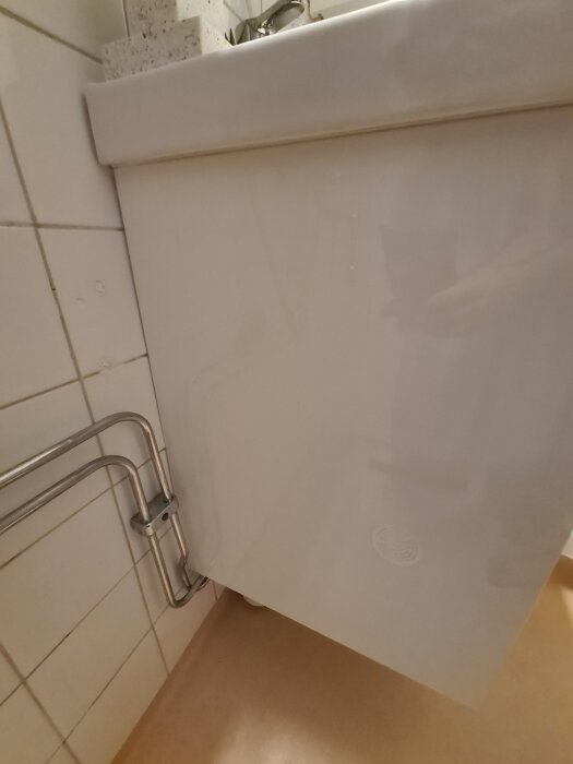 Vitt badrumsskåp med synliga rör vid sidan, inga nya dragningar.