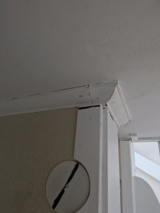 Foder som möter taklist i en hörna, med synliga skarvar och eventuellt ojämna kanter, i ett hus.