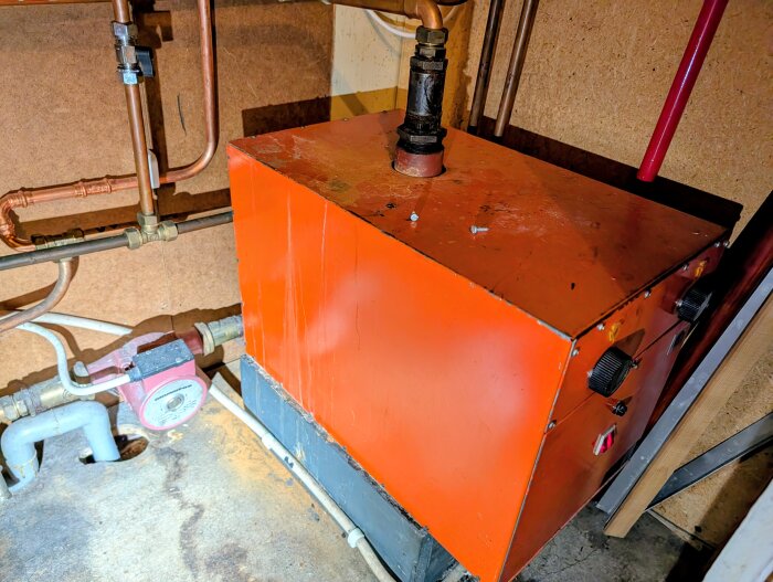Orange Frico elpanna med rör och vred i källarutrymme, används för grundvärme i äldre hus i Sveg.