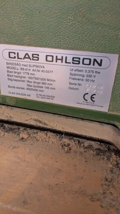 Skylt på en bandsåg från Clas Ohlson med specifikationer som modell BS-614, bladhastighet, sågkapacitet och elektriska krav; CE-märkt.