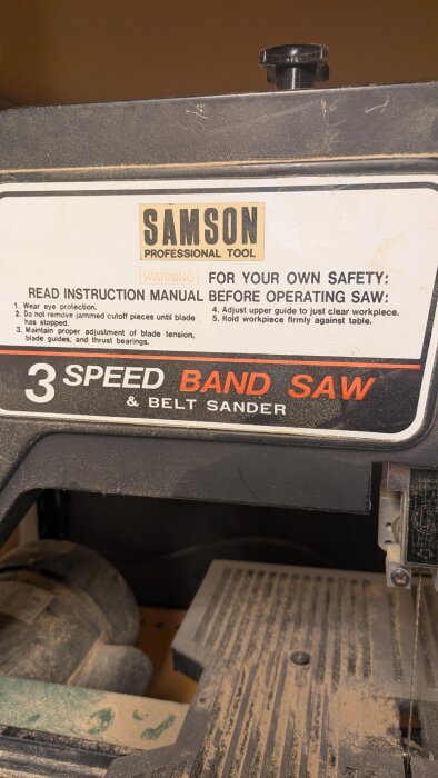 Samson bandsåg med etikett som visar säkerhetsinstruktioner och texten "3 Speed Band Saw & Belt Sander".