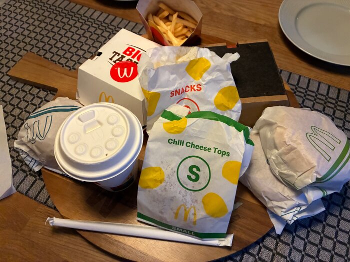 Snabbmat från McDonald's på ett bord, inklusive hamburgare, pommes frites, dryck och snacks.