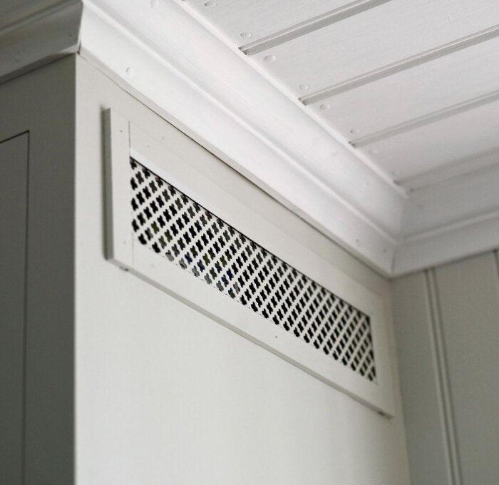 Ventilationsgaller installerat på köksskåpets sida nära taket, för förbättrad luftcirkulation ovanför en integrerad kyl och frys.