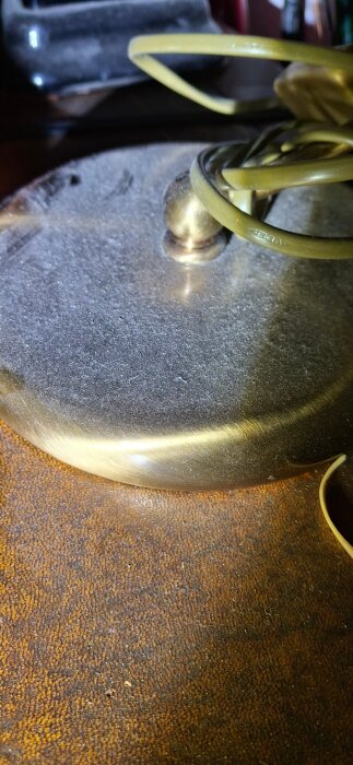Närbild av en gammal metallcylinder med dammig yta och gula kablar ovanpå, troligen del av ett äldre källarinstallationssystem.