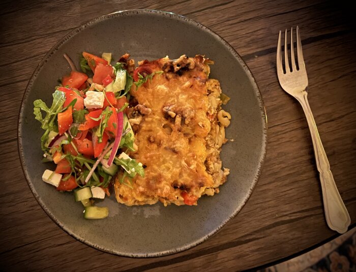 Tallrik med lasagne och sallad, bestick vid sidan.