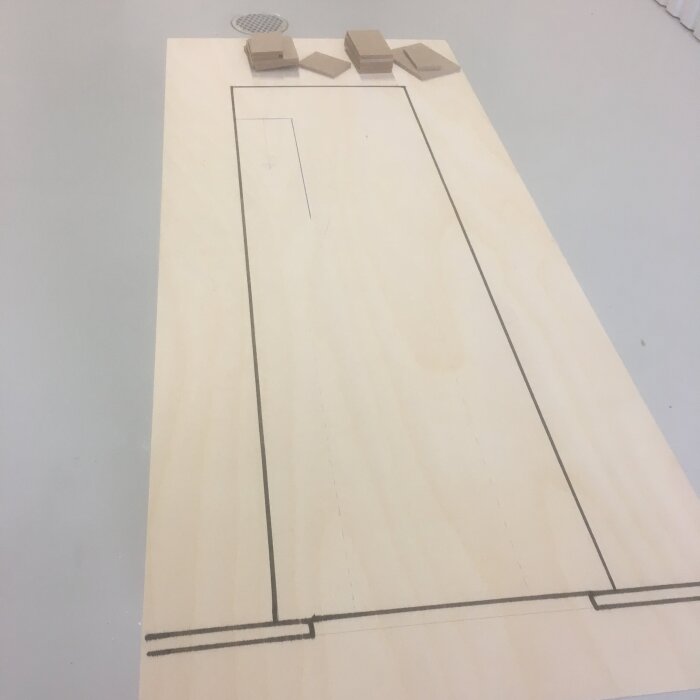 Skalenlig ritning på en skiva med små masonitbitar ovanpå, för planering av lokalens layout.
