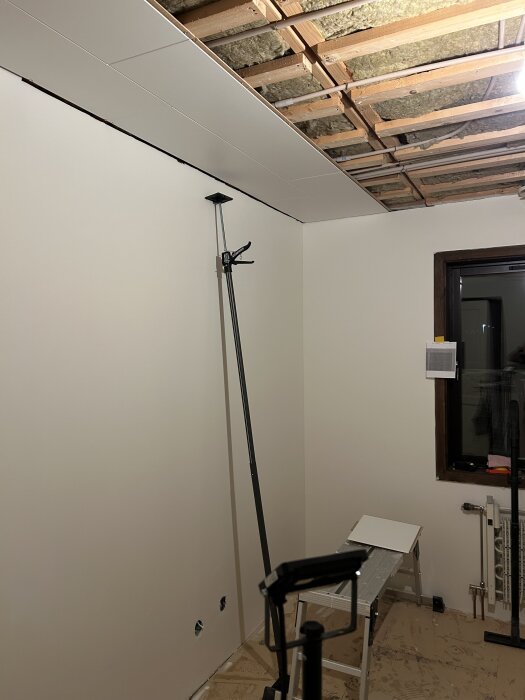 Rum under renovering med avluftat innertak, monteringsstöd och stege.
