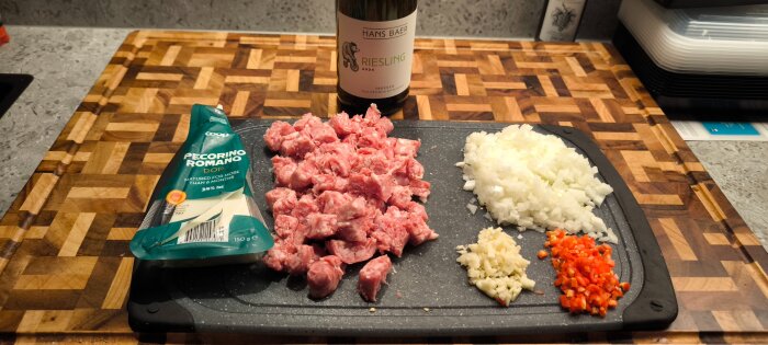 Hackat kött och grönsaker på skärbräda med pecorinoost och en flaska Rieslingvin i köket.