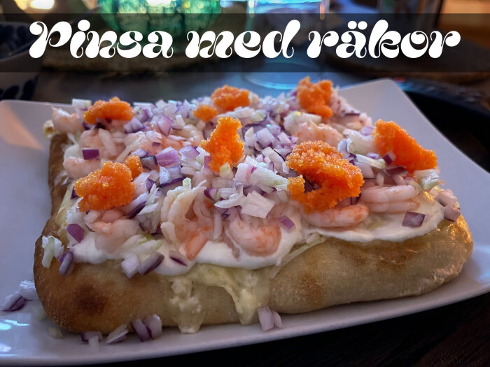 Pinsa med räkor, lök och rom på en tallrik, smakfullt presenterad med text "Pinsa med räkor" i dekorativ stil ovanför.