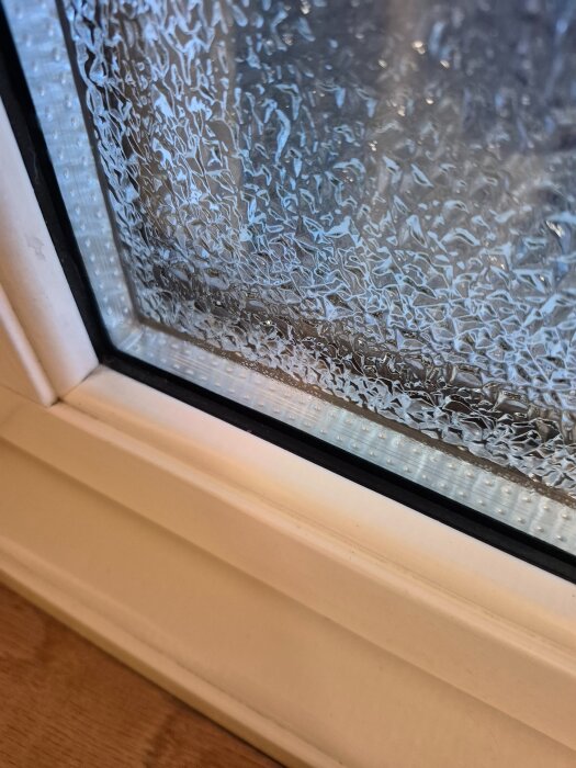 Sprucken fogning och målning runt ett fönster, visar tecken på skador antagligen orsakade av temperaturskiftningar.