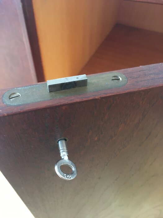 Möbellås med nyckel insatt i låst läge, där låsregeln är synlig och dörren delvis öppen.