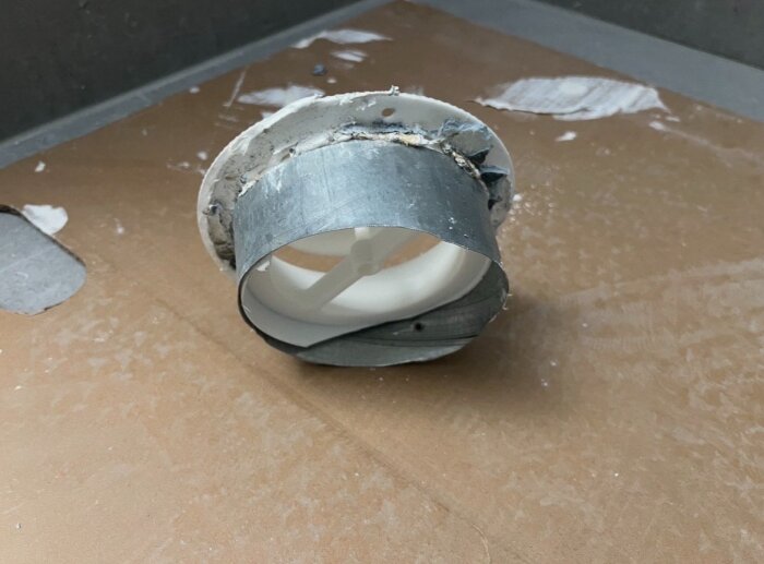Ventilationsrör som är löst monterat på gipsdon, med sprickor i fogen. Röret syns ovanpå en skiva i ett pågående renoveringsprojekt.