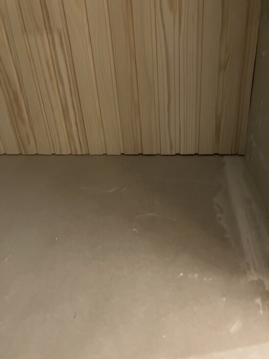 Spontad furupanel monterad i ett badrumstak, visar max 2 mm utrymme för expansion vid väggen.