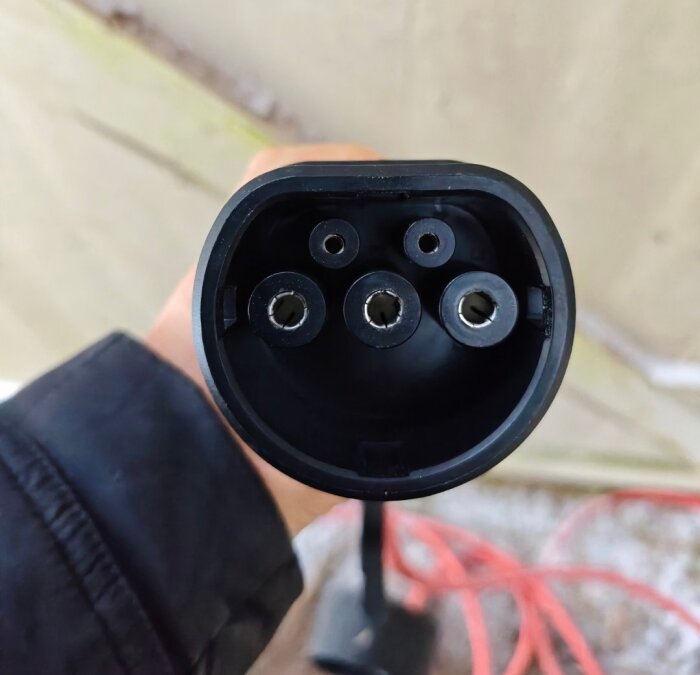 Kabelkontakt för elanslutning med fem stift, hålls av en hand.