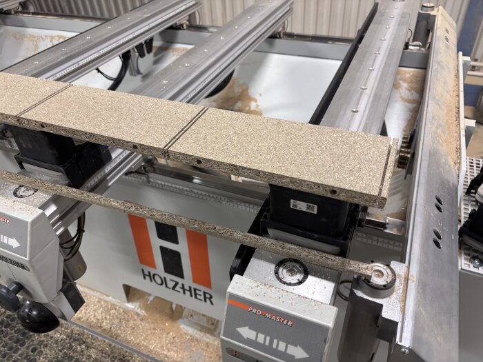 Träskiva på en CNC-maskin av märket Holzher, används för att tillverka svängda luckor enligt beskrivning i text om byggprojekt.