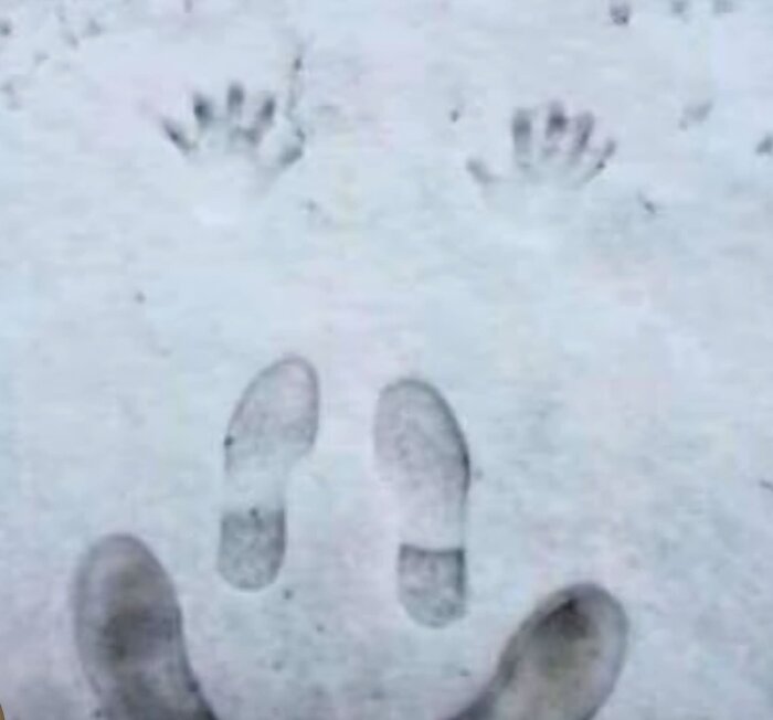Fotspår i snön bildar ett ansikte med handavtryck som ögon.