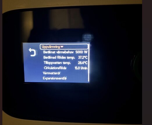 Display på värmepump visar: Beräknat värmebehov 5000 W, beräknad flödestemperatur 37.2°C, tilloppstemperatur 28.4°C, cirkulationsflöde 15.0 l/min.