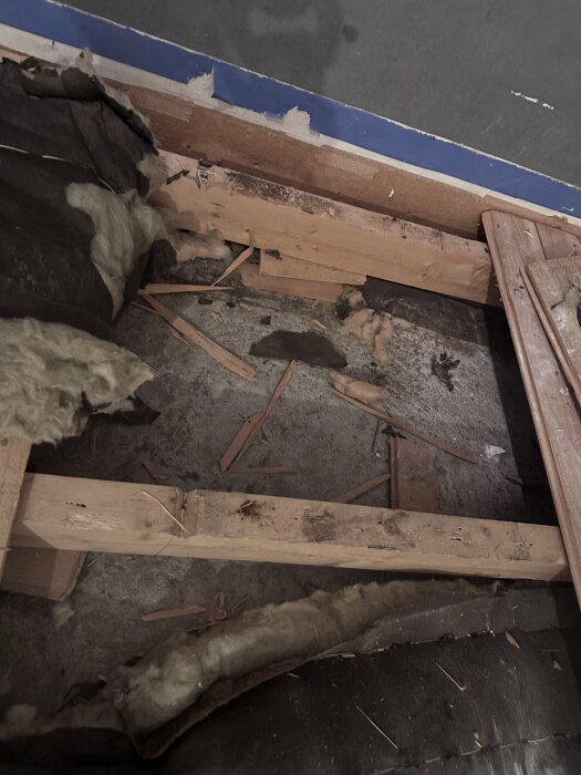 Golv under renovering med synliga träreglar, betongplatta och isoleringsmaterial i rum från hus byggt 1971.