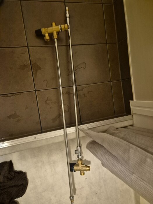 Rörkopplingar och ventiler på ett kaklat golv, sidovy.