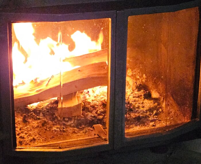 En vedbit brinner i en kamin, omgiven av flammor och glödande kol.