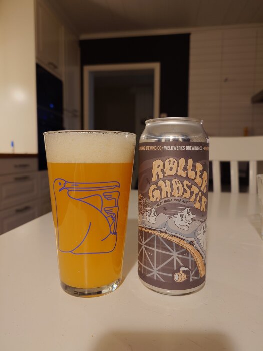 Ett glas med NEIPA-öl från Weldwerks bredvid en burk märkt "Roller Ghoster" står på ett bord i ett kök.