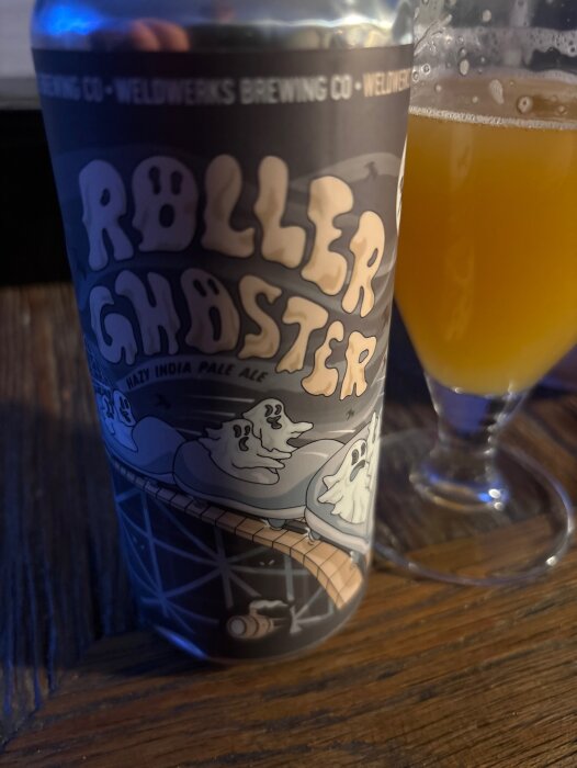 Ölburk med texten "Roller Ghoaster" och illustration av spöken i berg- och dalbana bredvid ett glas öl.