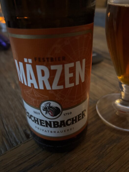 Flaska och glas med Eschenbacher Märzen Festbier på ett träbord.