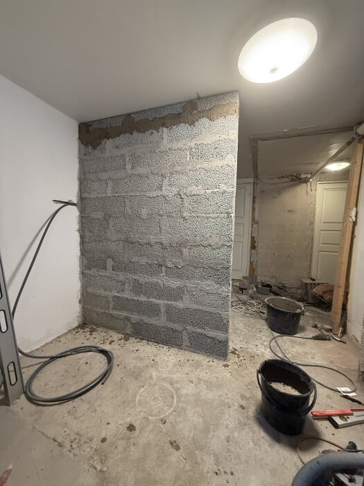 Vägg under konstruktion med exponerade betongblock och verktyg runtomkring, redo för flytspackling.