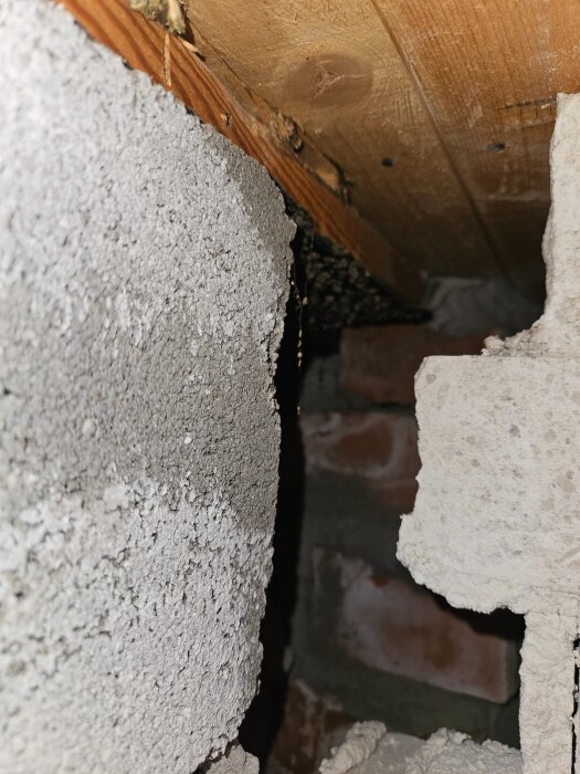Byggdetalj med exponerad träbalk och murverk, visar potentiell skada eller reparation vid konstruktion eller renovering.