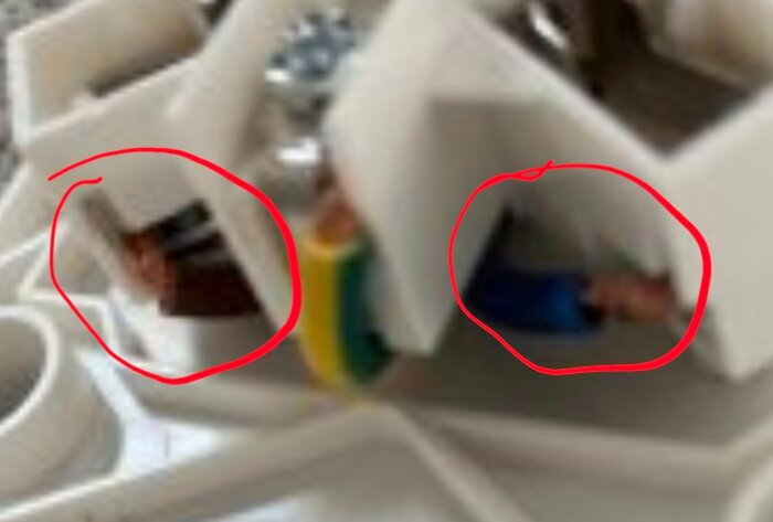 Elektrisk kopplingspunkt med brun och blå kabel innanför röda markeringar, potentiella fel att åtgärda.