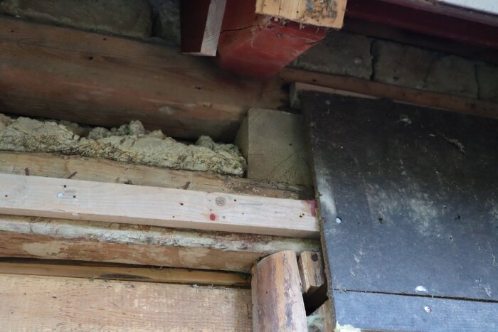 Gammal takstol och väggstruktur med bjälkar; inspektionsbild för renovering med synligt trä och isoleringsmaterial.