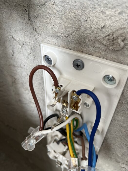 Väggmonterad elinstallation med synliga färgade kablar anslutna till en kopplingsplint.