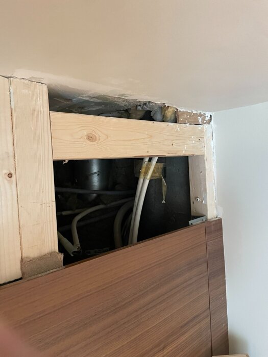 Hål i väggen med trästomme och synliga ventilationsrör och kablar, förberett för koppling till frånluftsdon i köksrenovering.