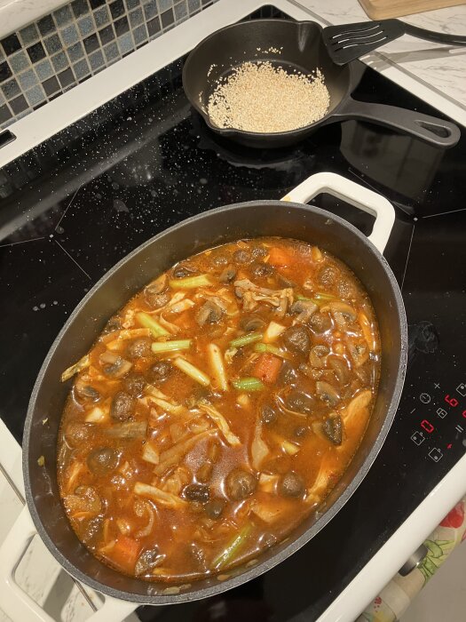 Koreansk hot pot med potatis, morot, svamp, salladslök, spetskål i kryddig sås; gochujang, misopasta, gochugaru. Toppar med rostade sesamfrön.