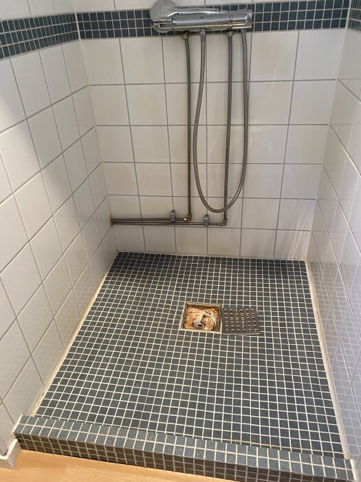 Tätskikt runt golvbrunn i dusch med blå mosaikplattor, felaktigt skuret och ej korrekt anslutet enligt besiktningsprotokoll.