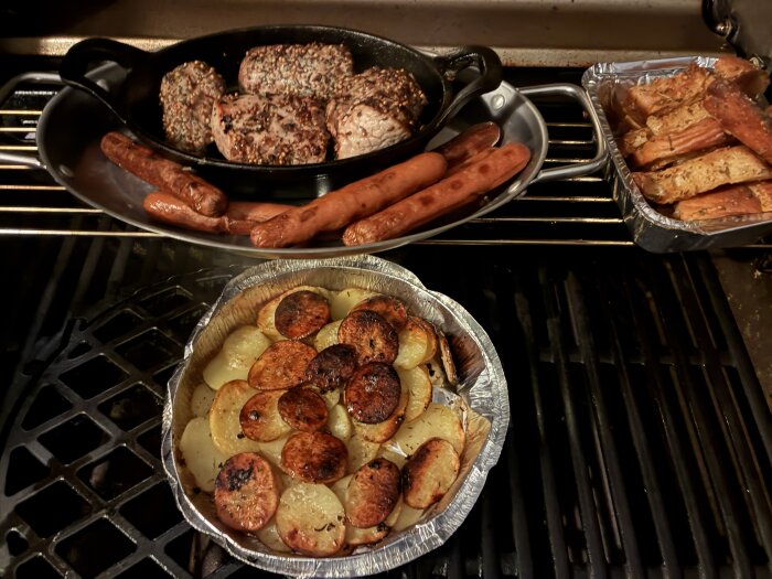 Ugnsplåt med stekt kött, korv och rostad potatis. Bakformar med gratinerat bröd och grönsaker på en spis.