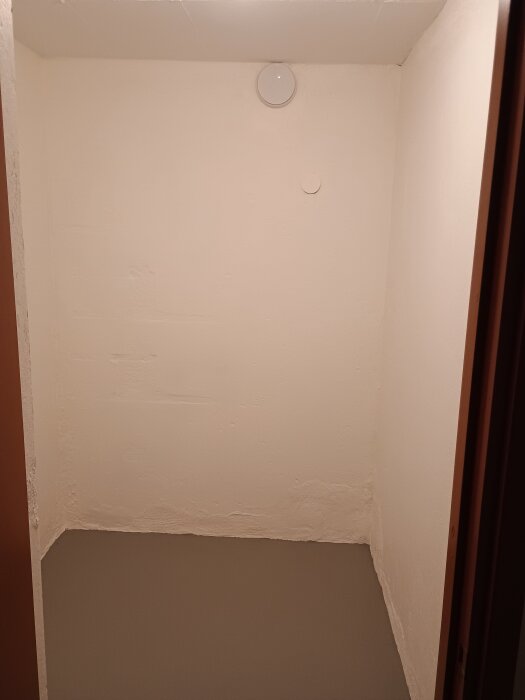 Matkällare med nymålade vita väggar och grått golv.