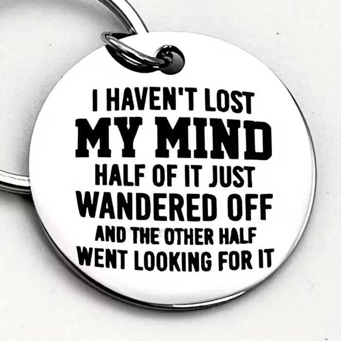 Nyckelring med texten "I haven't lost my mind, half of it just wandered off and the other half went looking for it" i svart på silverfärgad bakgrund.