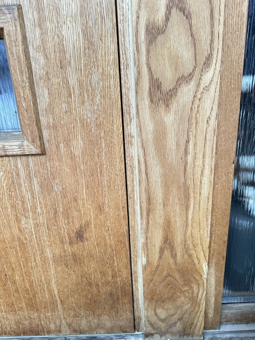Närbild på en träytterdörr som inte ligger i linje, vilket orsakar att den slår i ramen när den stängs.