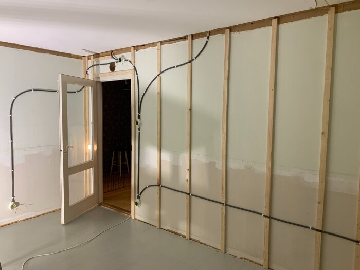 Renovering av sovrum med synlig existerande träpanel, nylagd eldragning och öppen dörr till nästa rum.