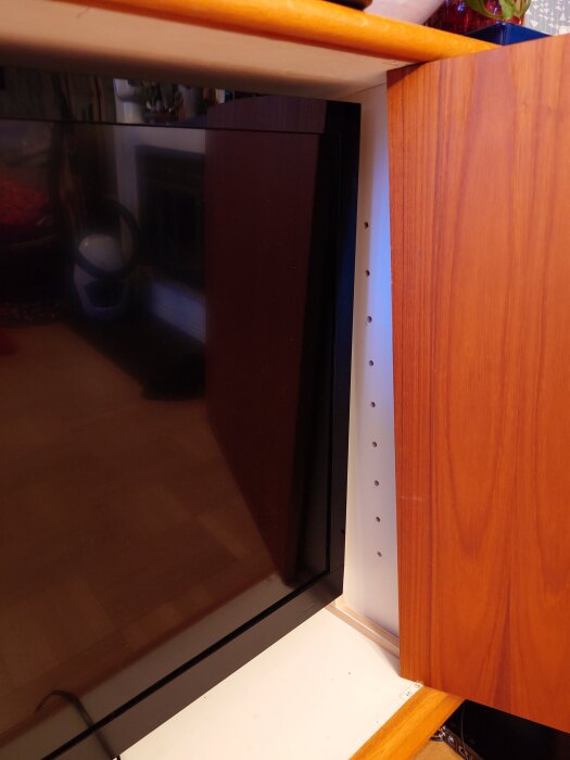 TV i ett skåp med justerbar arm, omgiven av träpanel.